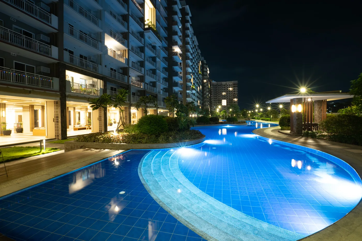 Lounge pool at Satori Residences lit at night with the towers behind